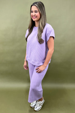 Woman wearing a purple outfit standing against a green background