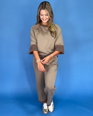 Woman wearing a beige outfit against a blue background