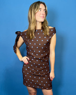 Chocolate brown mini dress with blue polka dots, off-the-shoulder neckline, and statement shoulder tie detail.