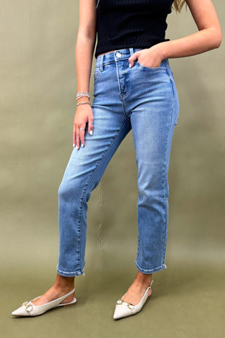 Person wearing blue jeans and a black top on a beige background