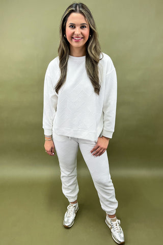 Woman wearing a white outfit with sneakers on a green background
