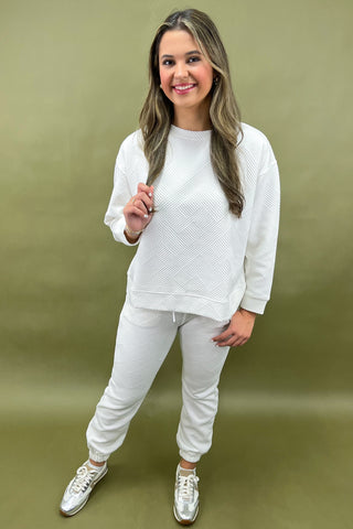 Woman wearing a white outfit with sneakers against a green background