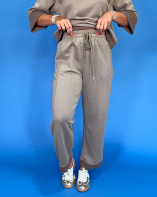 Person wearing gray sweatpants and a matching top on a blue background