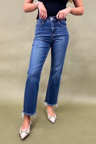 Person wearing blue jeans and white shoes on a beige background