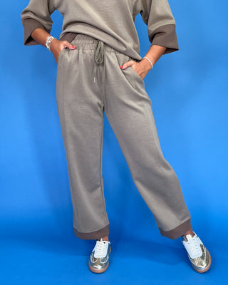 Person wearing gray sweatpants and a matching top against a blue background