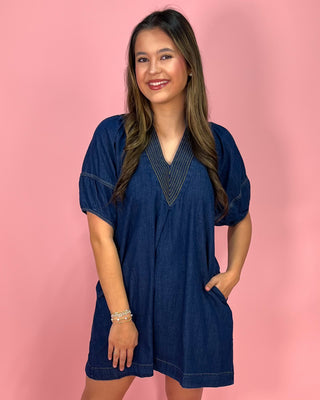 Woman wearing a blue dress against a pink background