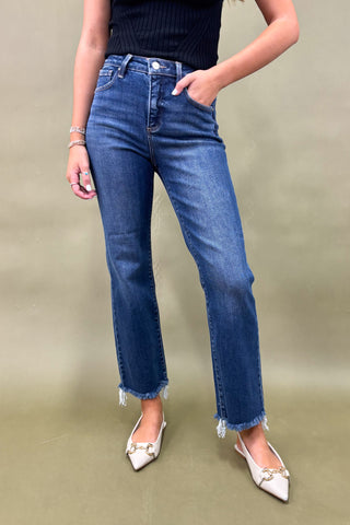 Person wearing blue jeans and white shoes on a plain background