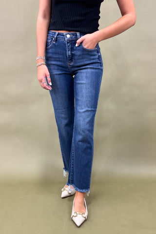 Person wearing blue jeans and a black top on a plain background