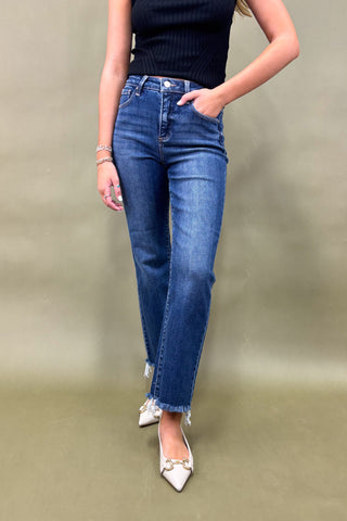 Person wearing blue jeans and a black top on a plain background