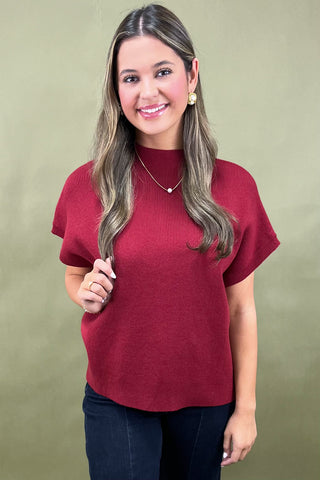 Woman wearing a red sweater against a beige background