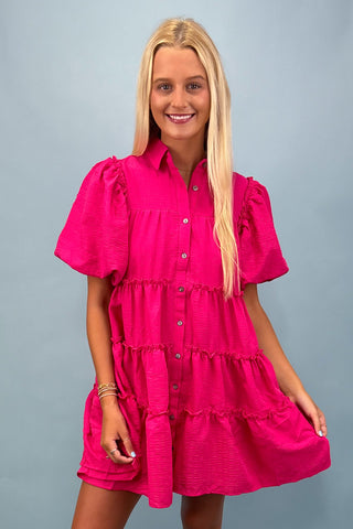 Woman wearing a bright pink dress against a gray background