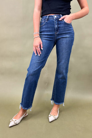 Person wearing blue jeans and white shoes on a beige background