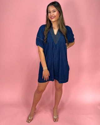 Woman wearing a blue dress against a pink background