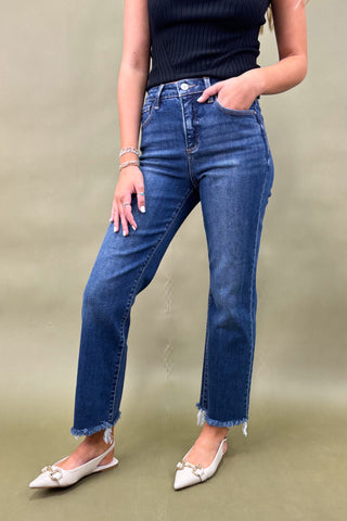 Person wearing blue jeans and a black top on a beige background