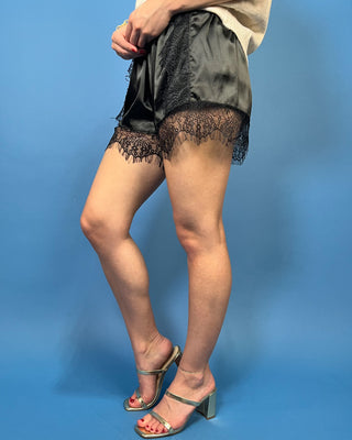 Black satin shorts with delicate lace panels, scalloped lace trim, and a comfortable elastic waist.