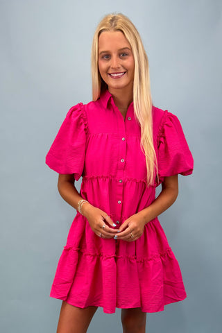 Woman wearing a bright pink dress against a gray background