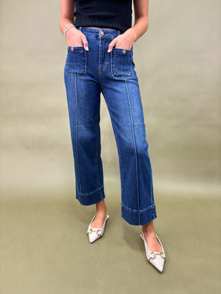 Person wearing blue jeans and white shoes on a beige background
