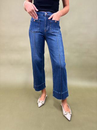 Person wearing blue jeans and white shoes on a green background