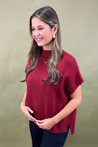 Woman wearing a red poncho against a beige background