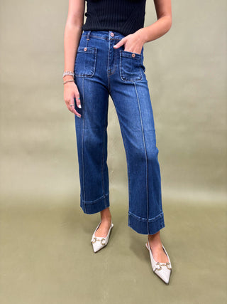 Person wearing blue jeans and white shoes on a plain background