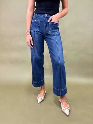 Person wearing blue jeans and white shoes on a beige background