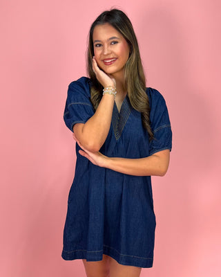 Woman wearing a blue dress against a pink background