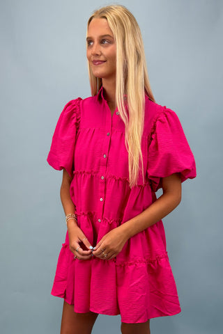 Woman wearing a bright pink dress against a gray background