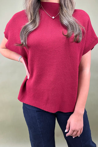 Person wearing a red sweater and blue jeans against a plain background