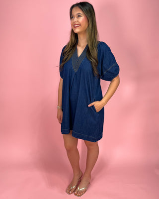 Woman wearing a blue dress against a pink background