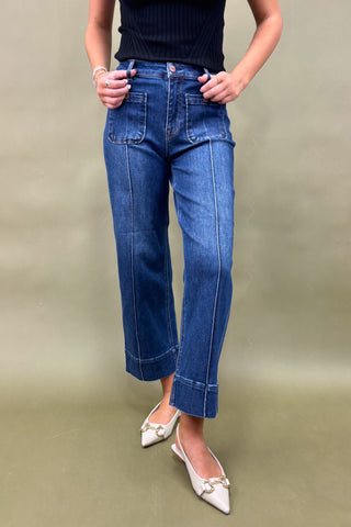 Person wearing blue jeans and white shoes on a plain background