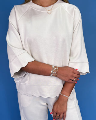 Person wearing a white outfit with jewelry against a blue background