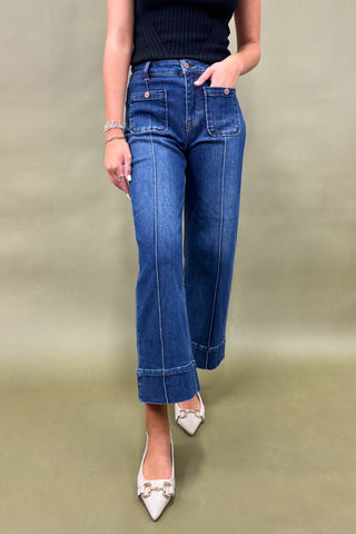 Person wearing blue jeans and white shoes on a plain background