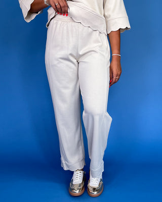 Person wearing white pants and a light-colored top on a blue background