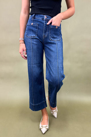 Person wearing blue jeans and white shoes on a beige background