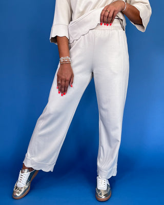 Person wearing white pants and a light-colored top on a blue background