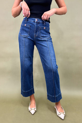 Person wearing blue jeans and a black top on a plain background