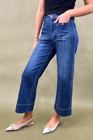 Person wearing blue jeans and white shoes on a beige background