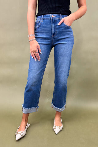 Person wearing blue jeans and white shoes on a plain background