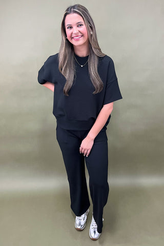 Woman wearing a black outfit against a plain background