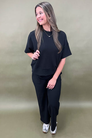 Woman wearing a black outfit against a plain background