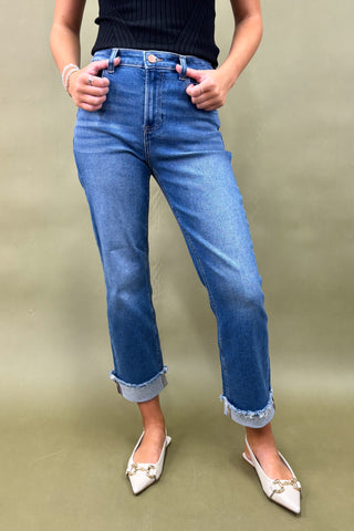 Person wearing blue jeans and white shoes on a plain background