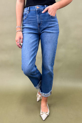 Person wearing blue jeans with a plain background