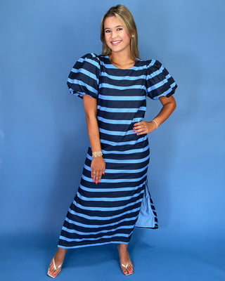 Woman wearing a blue and black striped dress against a blue background