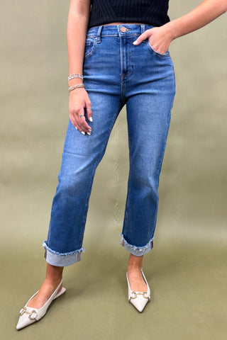 Person wearing blue jeans and white shoes on a green background