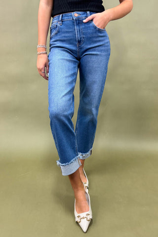 Person wearing blue jeans and white shoes on a plain background