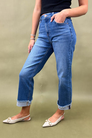Person wearing blue jeans and white shoes on a green background