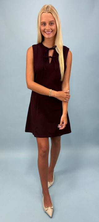 Woman wearing a dark sleeveless dress against a light blue background