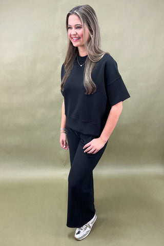Woman wearing a black outfit against a beige background