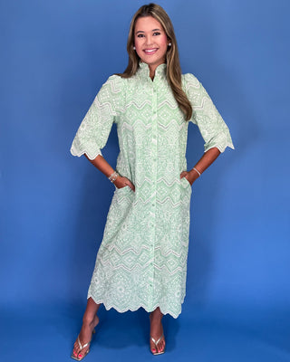 Woman wearing a light green lace dress against a blue background