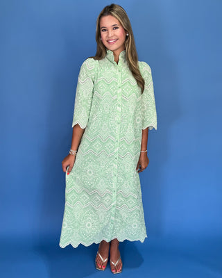 Woman wearing a green patterned dress against a blue background